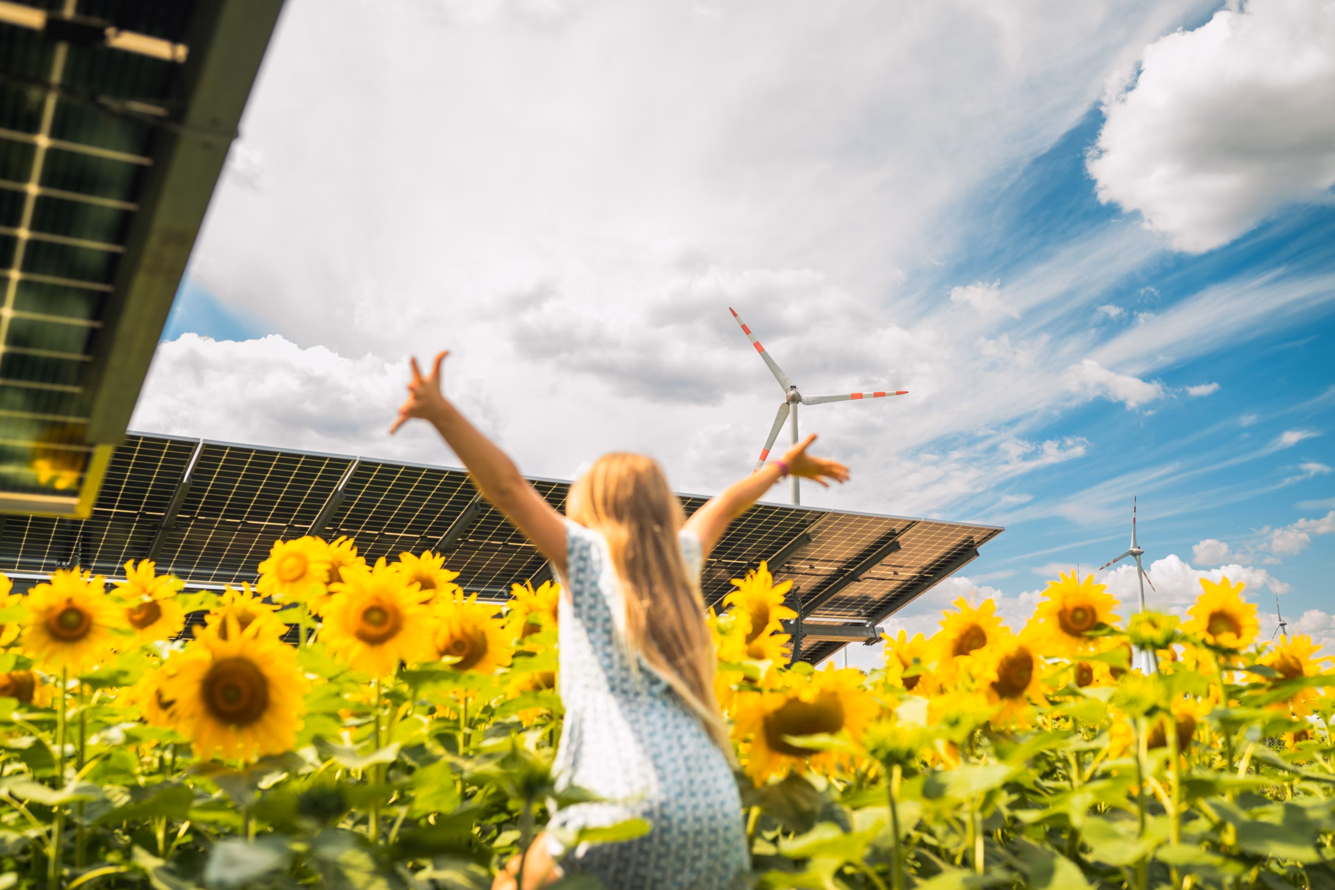 Junges Mädchen streckt die Hände in die Höhe am Sonnenblumenfeld