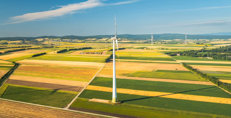 Drohnenaufnahme von einem Windrad auf einem Feld.